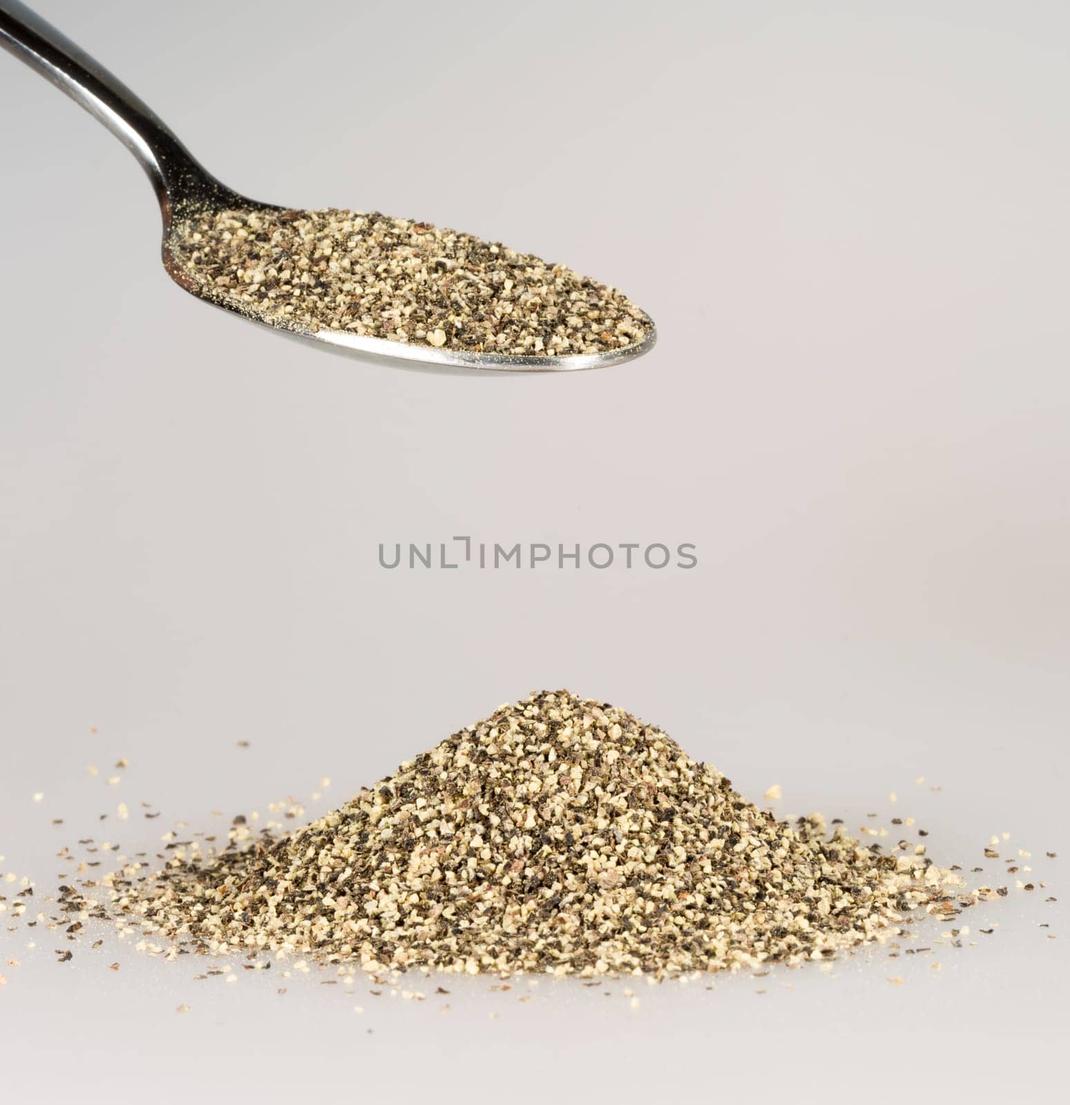 Ground Pepper on Tablespoon with a pile of black pepper beneath.