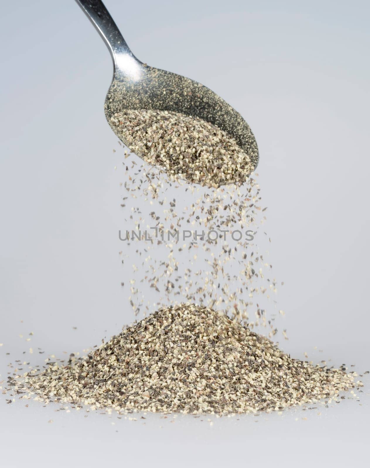 Black Pepper Falling from tablespoon close up.