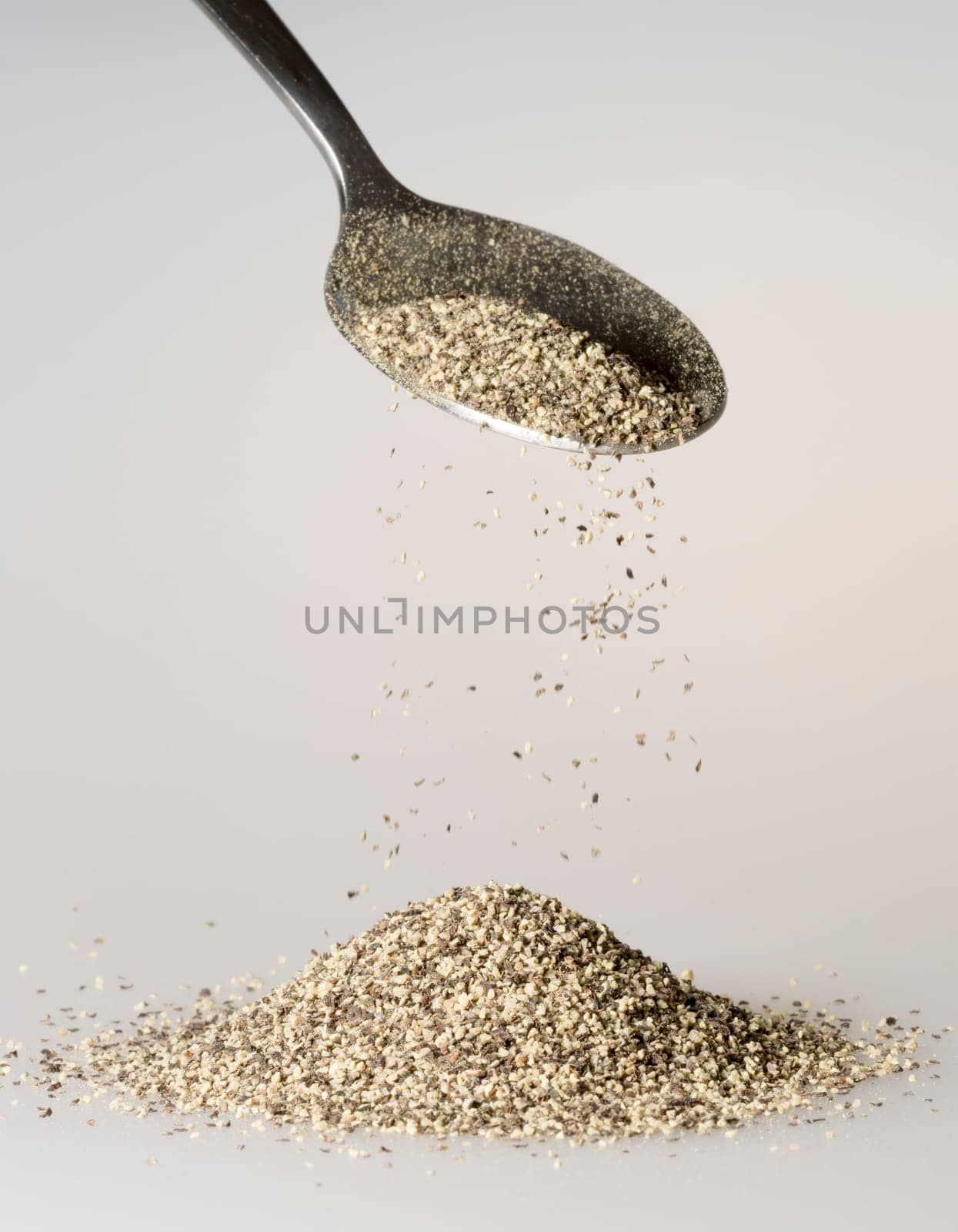 Black Pepper Falling from tablespoon close up.