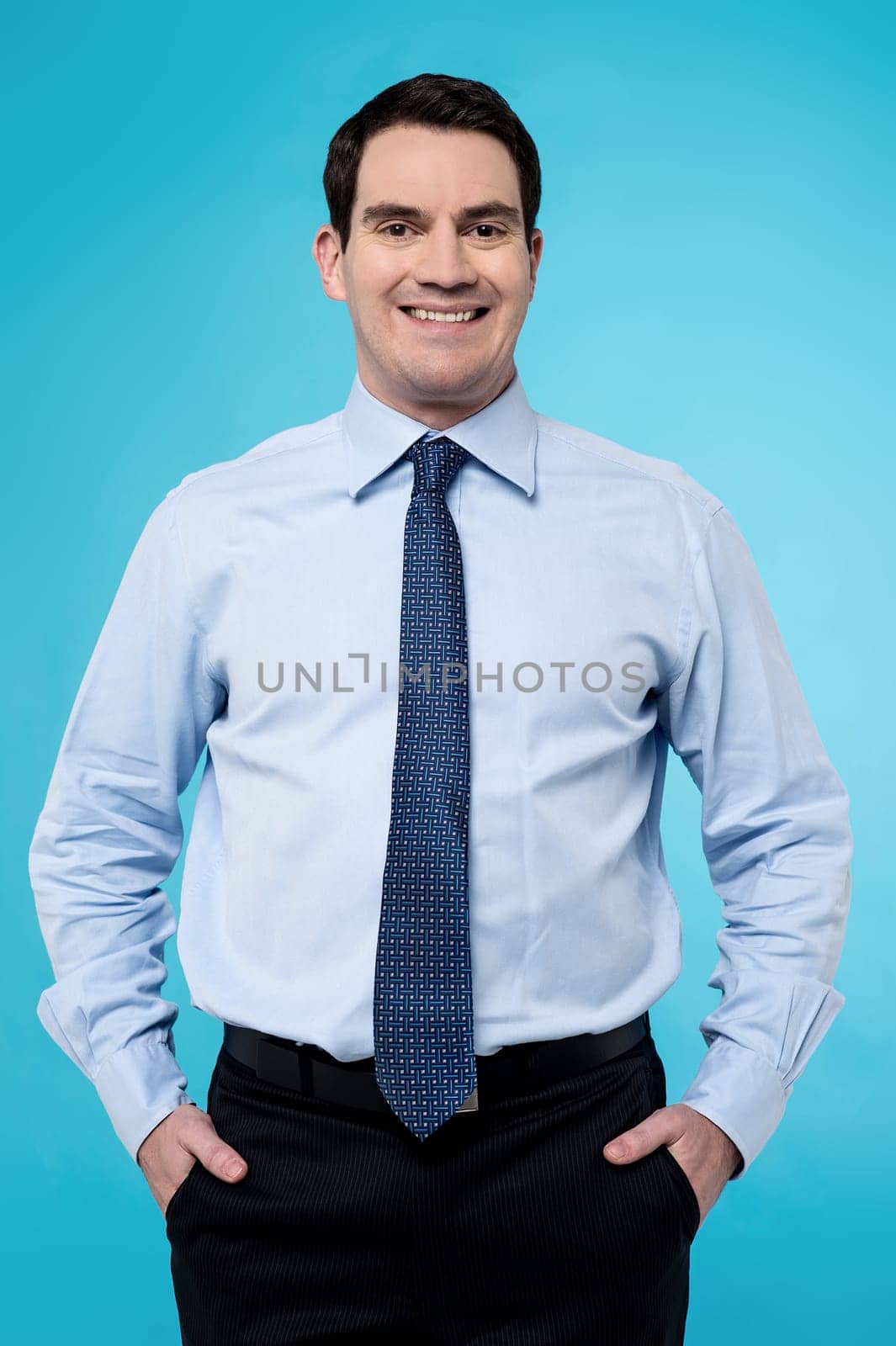 Confident businessman posing to camera against blue
