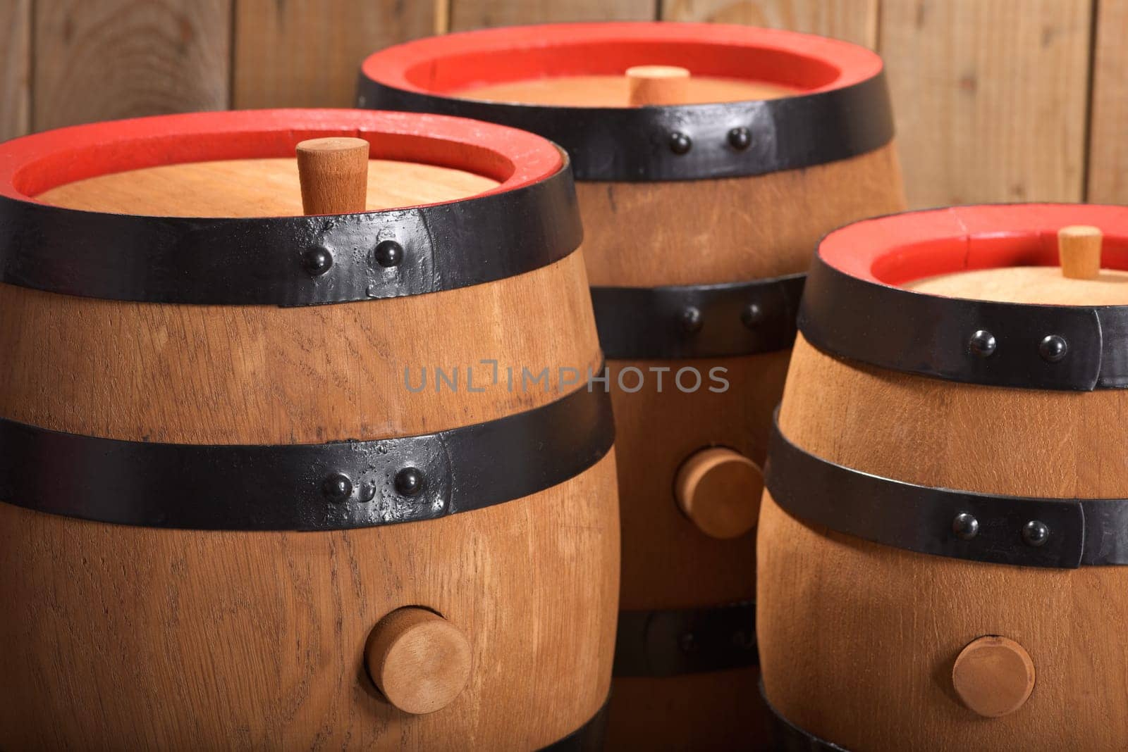 three old beer barrels with wooden plugs on a wooden background