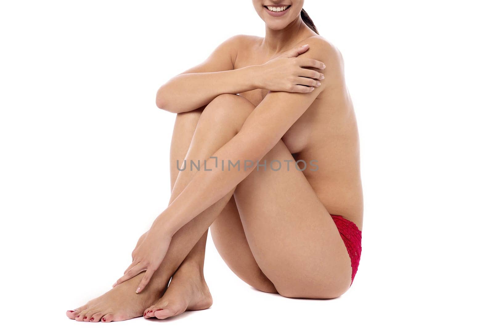 Topless young woman sitting on floor against white