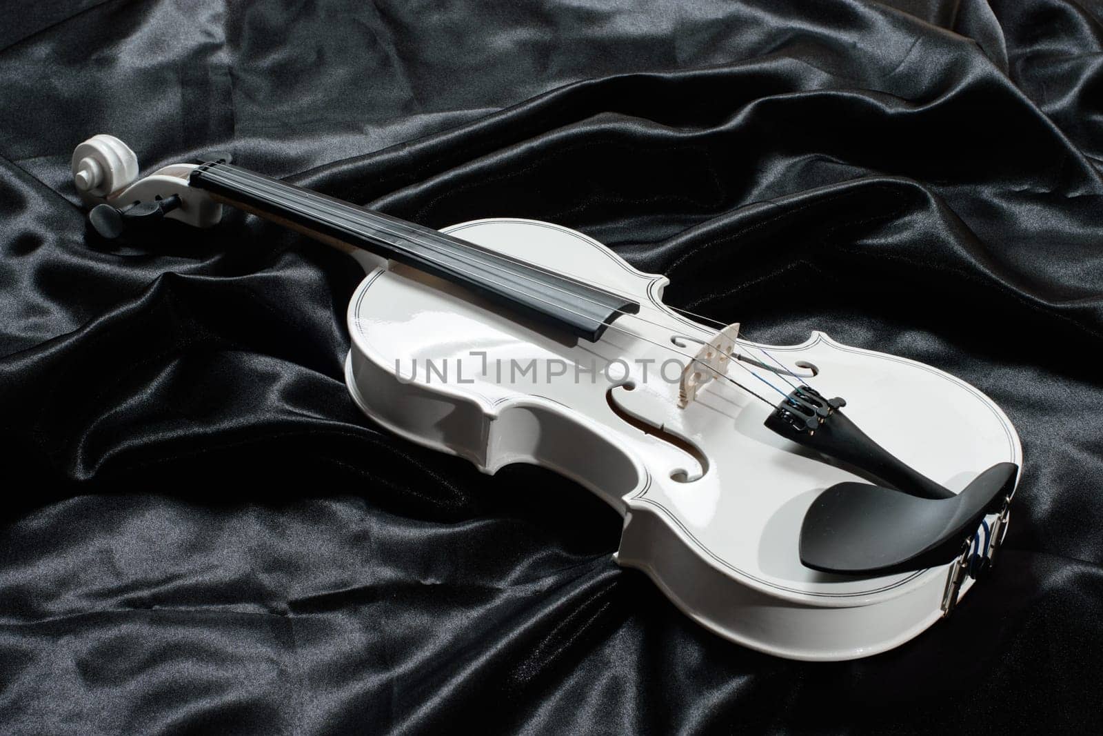 Closeup of a white violin on a background of black satin