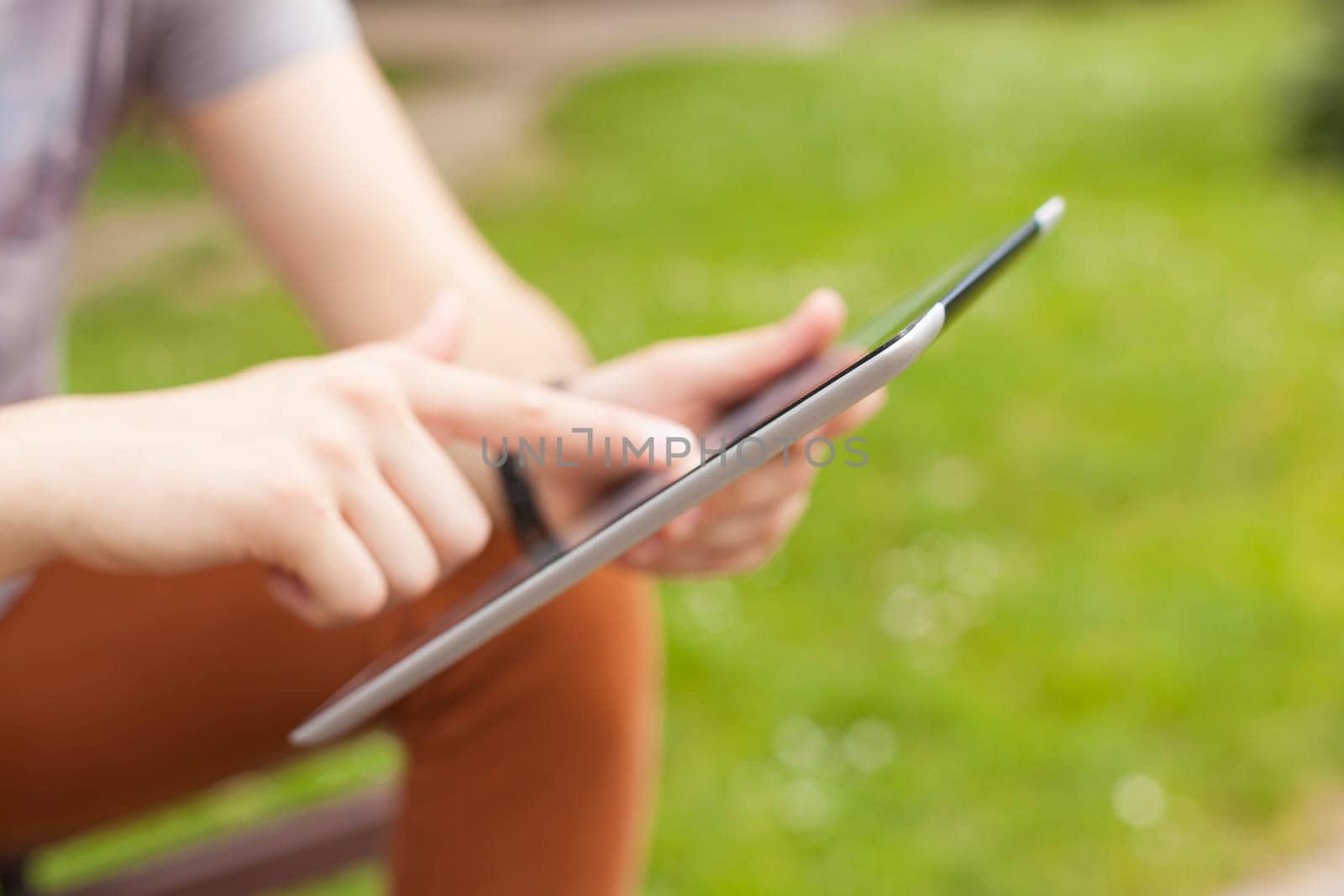 Young man read news and communicate on social networks with tablet computer in park