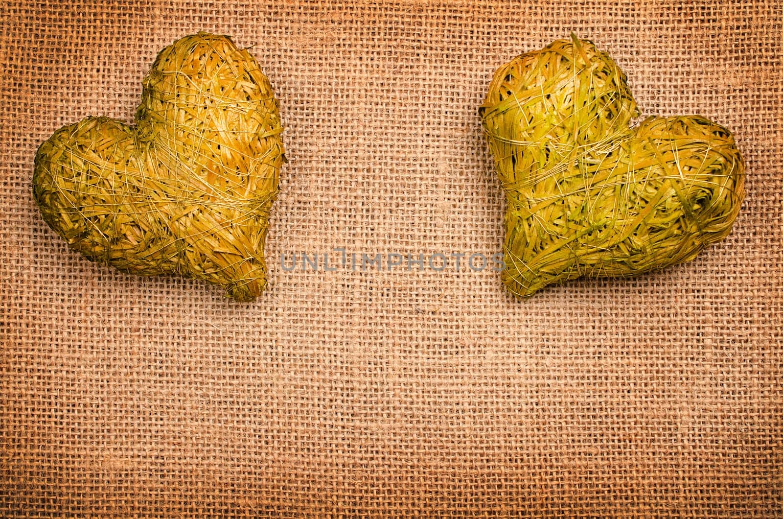 Burlap texture with two natural green heart shapes