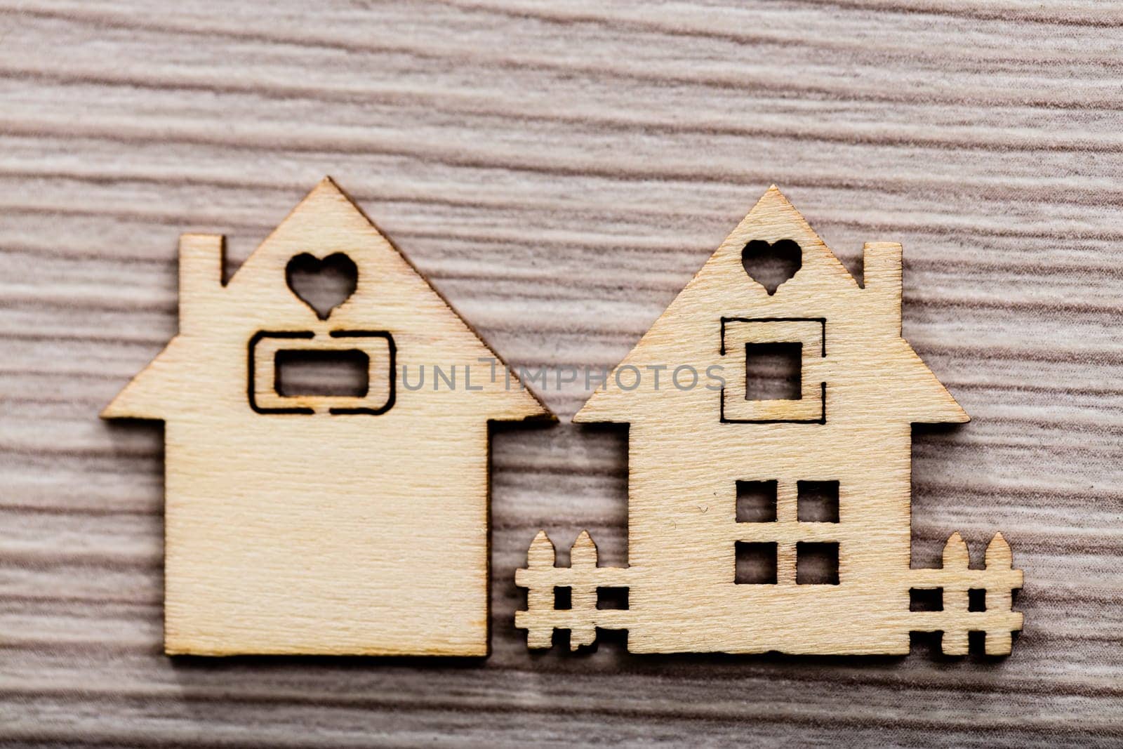 a couple of figures representing wooden little houses on a wooden bacground with a fence and a heart shaped window