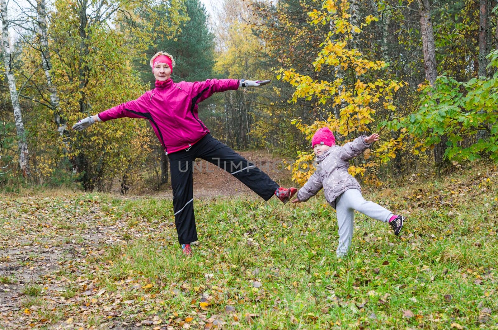 Woman with girl doing aerobics in the autumn park