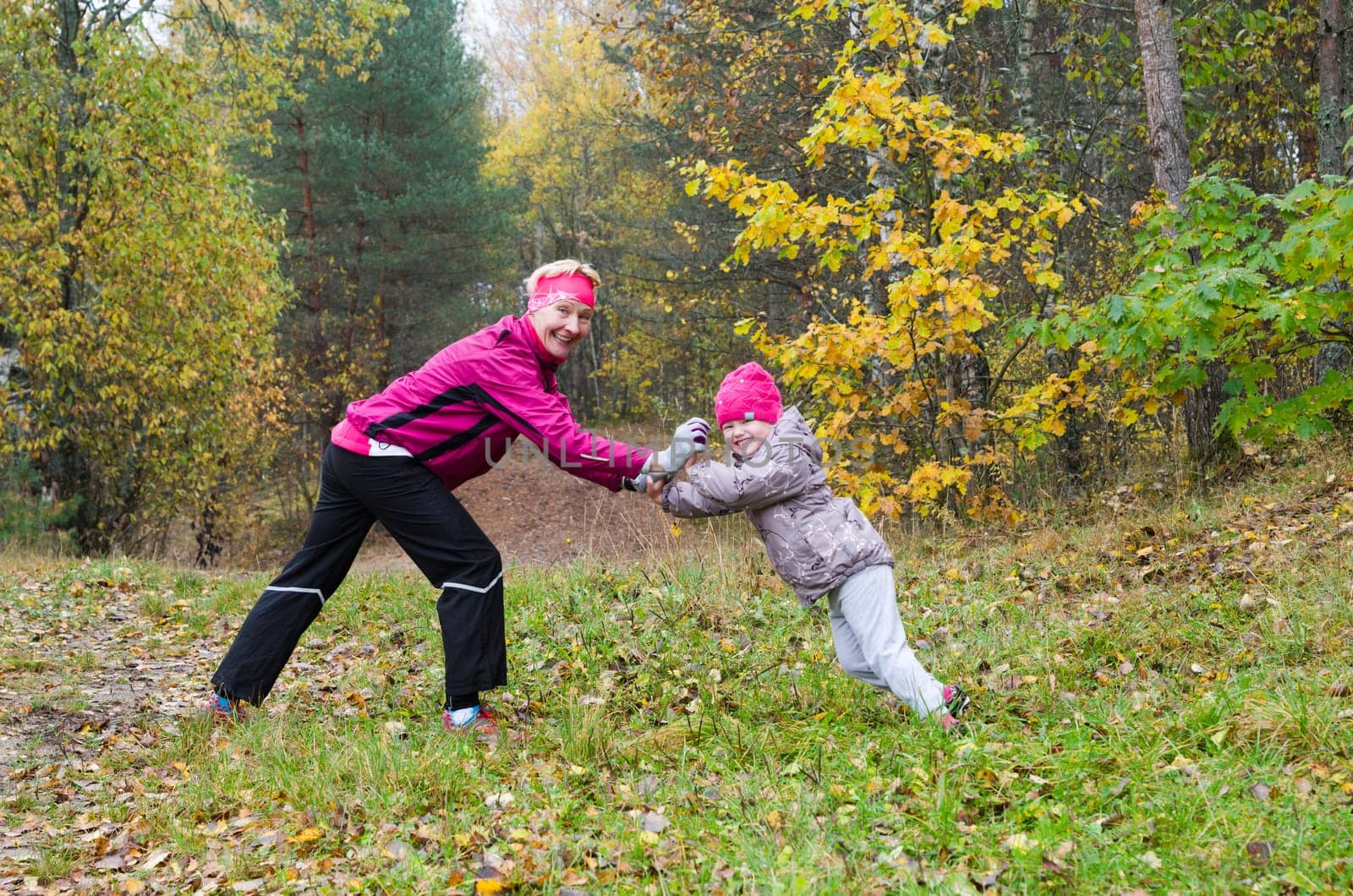 Woman with girl doing aerobics in the autumn park