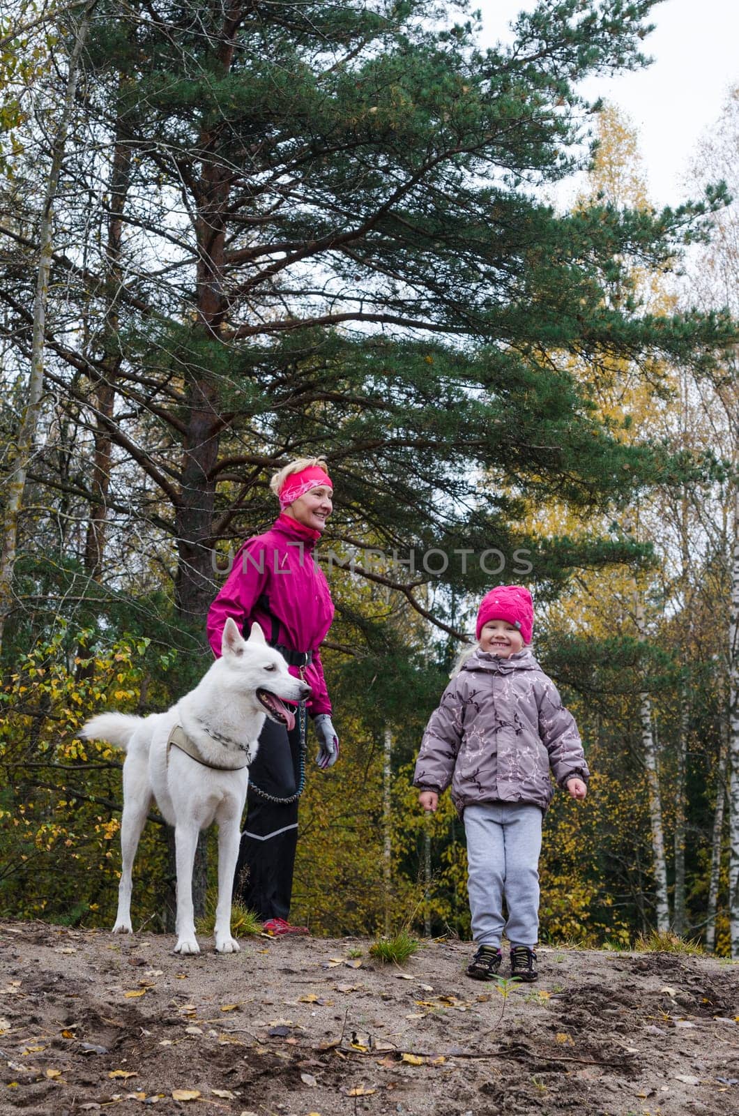 Granny with her granddaughter and a dog walk in autumn Park