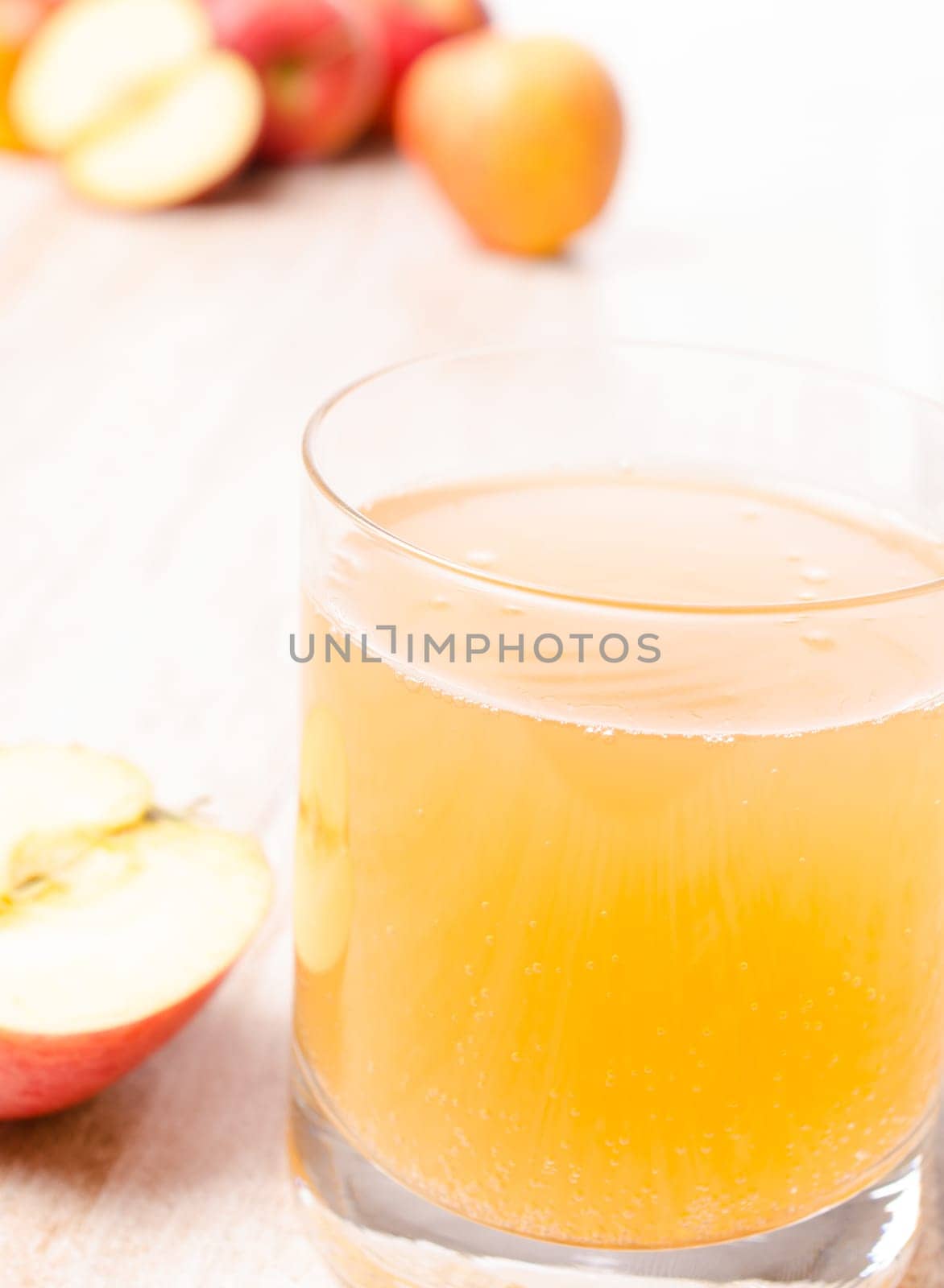 Glass of organic apple juice with fresh apples on a kitchen table