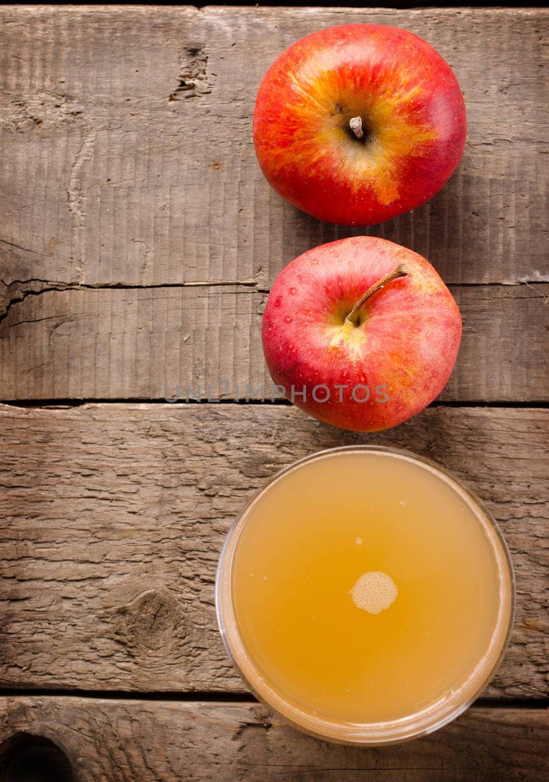 Organic apple juice with fresh red apples on a rustic wooden table