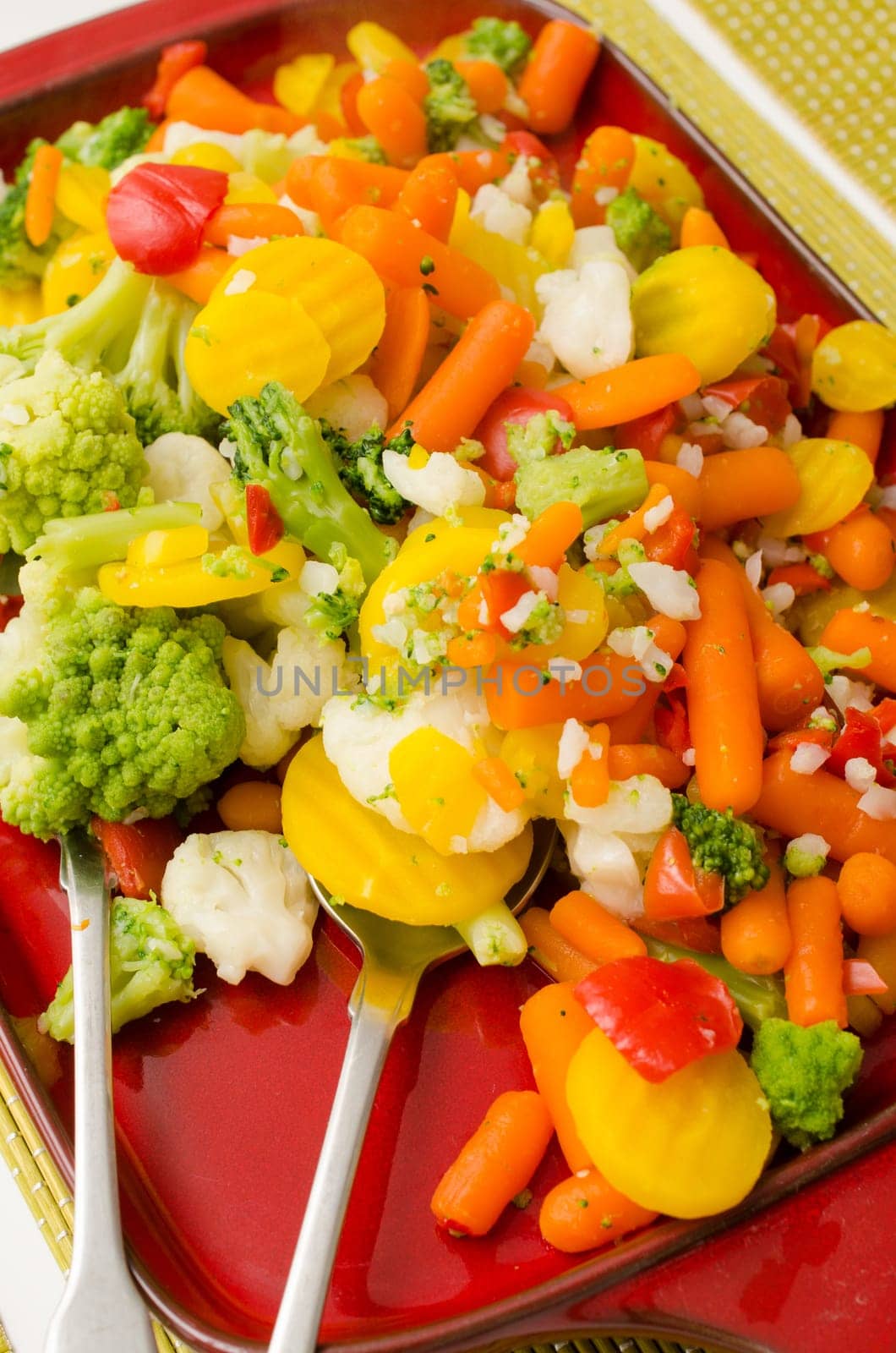 Delicious boiled vegetables on a red ceramic plate