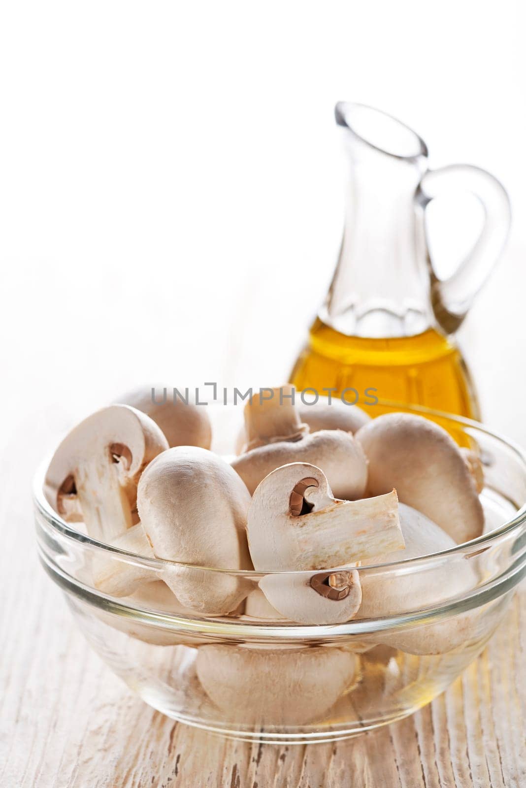 Mushrooms champignon and olive oil on white background.