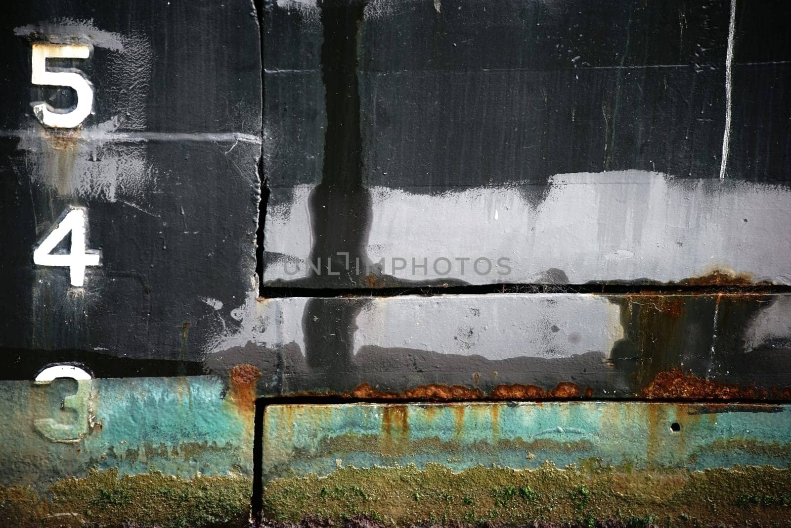 The close-up of a rusty and algae-covered ship wall of a tanker.