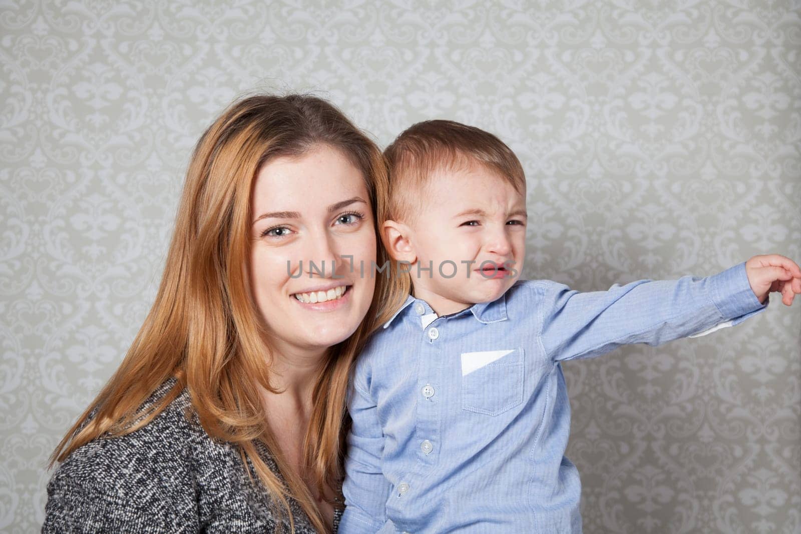 1 year old baby boy in his mother's arms, studio portrait.