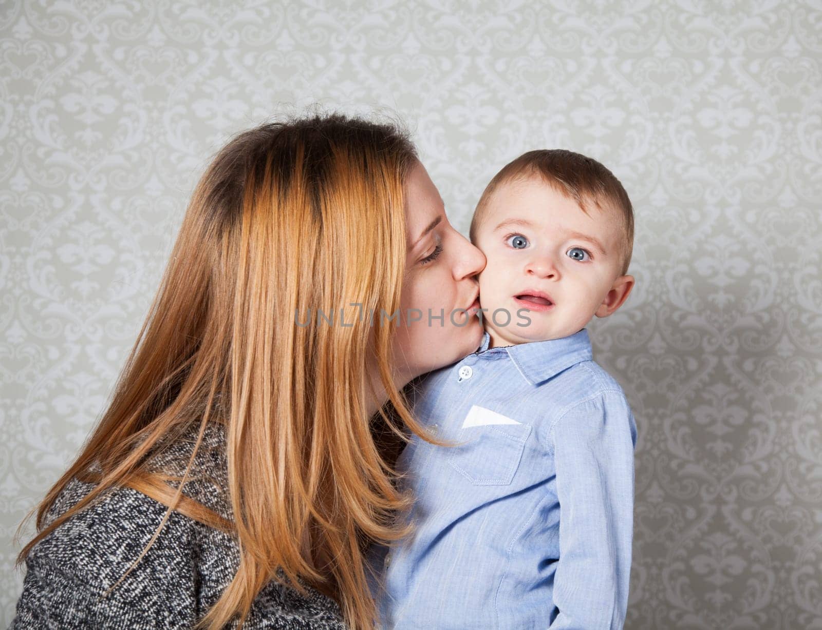 1 year old baby boy in his mother's arms, studio portrait.