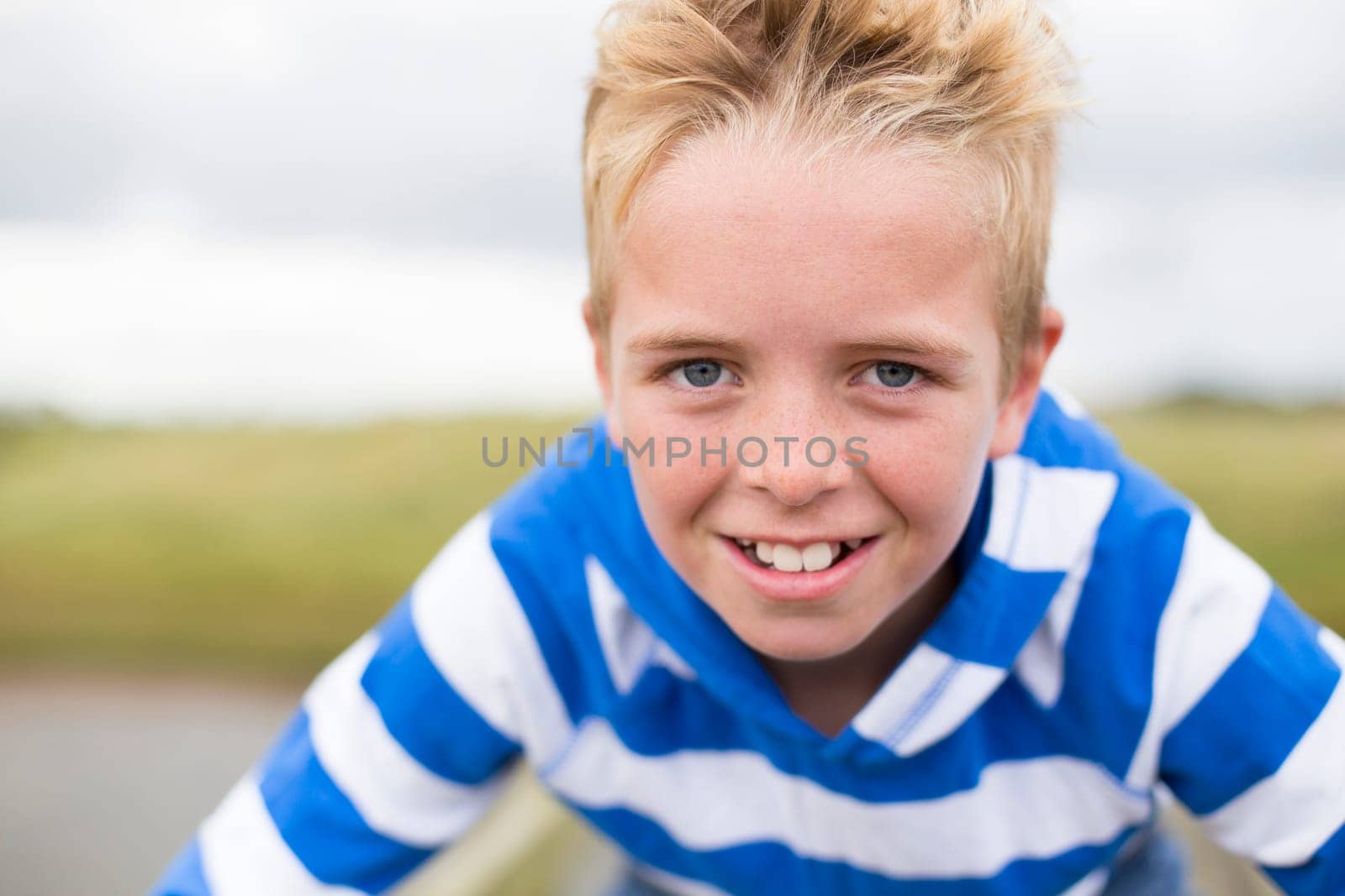 Portrait of a teenage boy smiling at the camera. He is outdoors and wearing casual clothing.