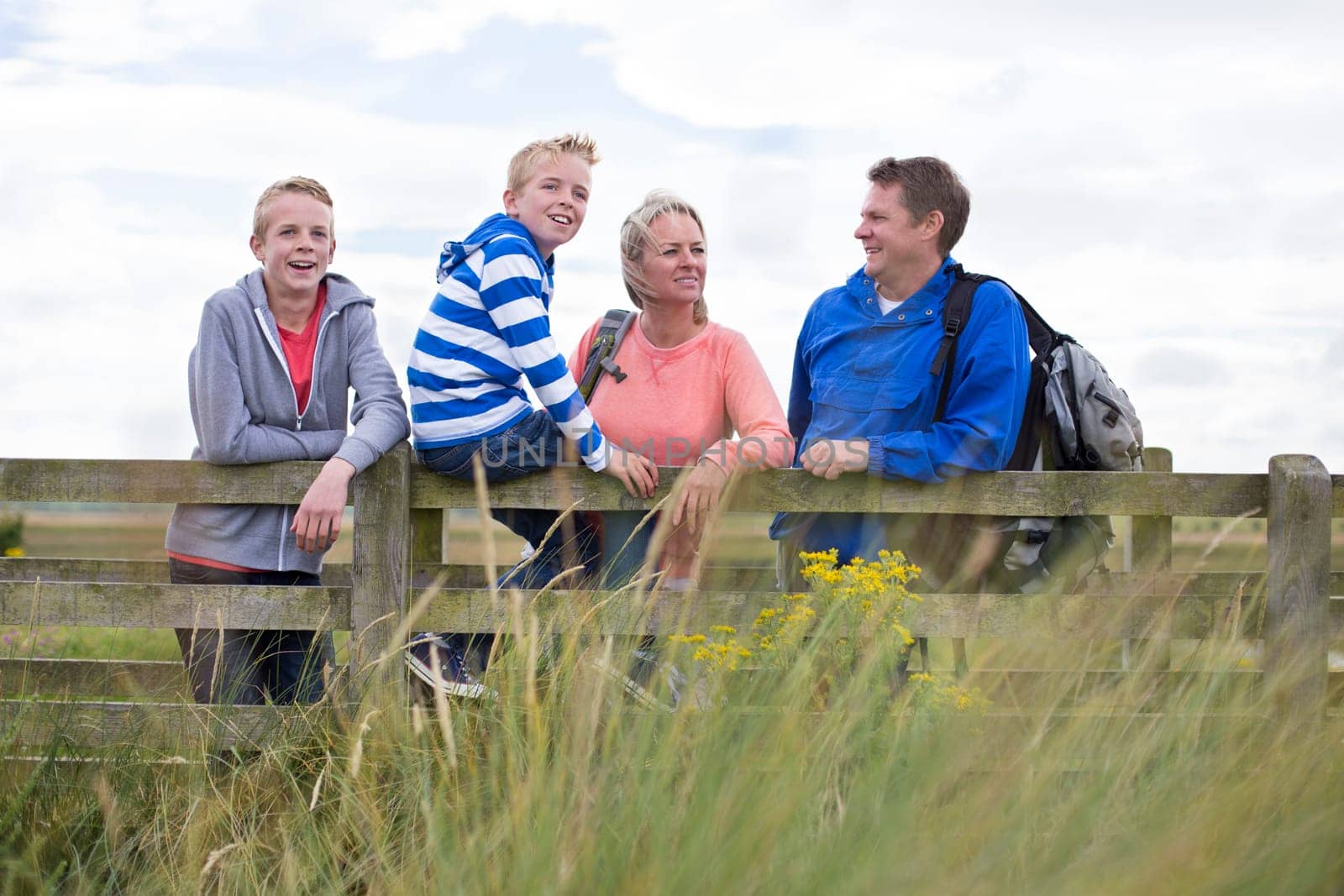 Happy Family of Four on a bridge. They are wearing casual clothing and looking at the surrounding area.