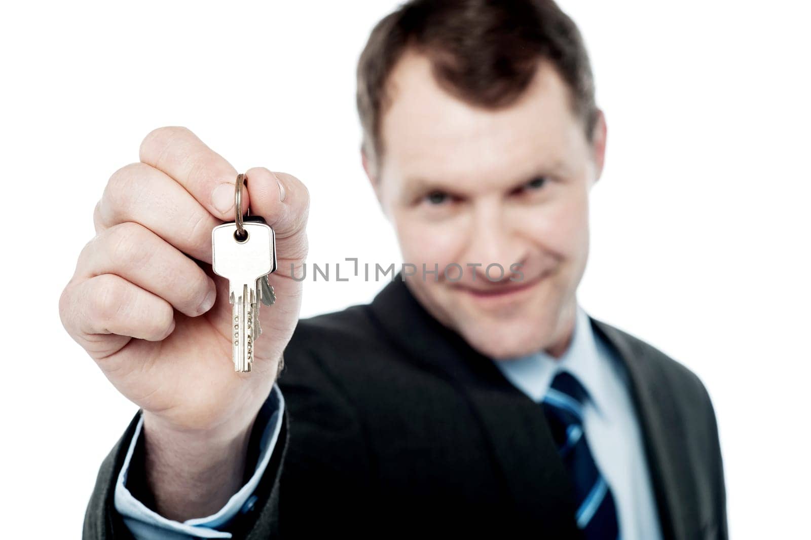 Handsome realtor offering house key over white