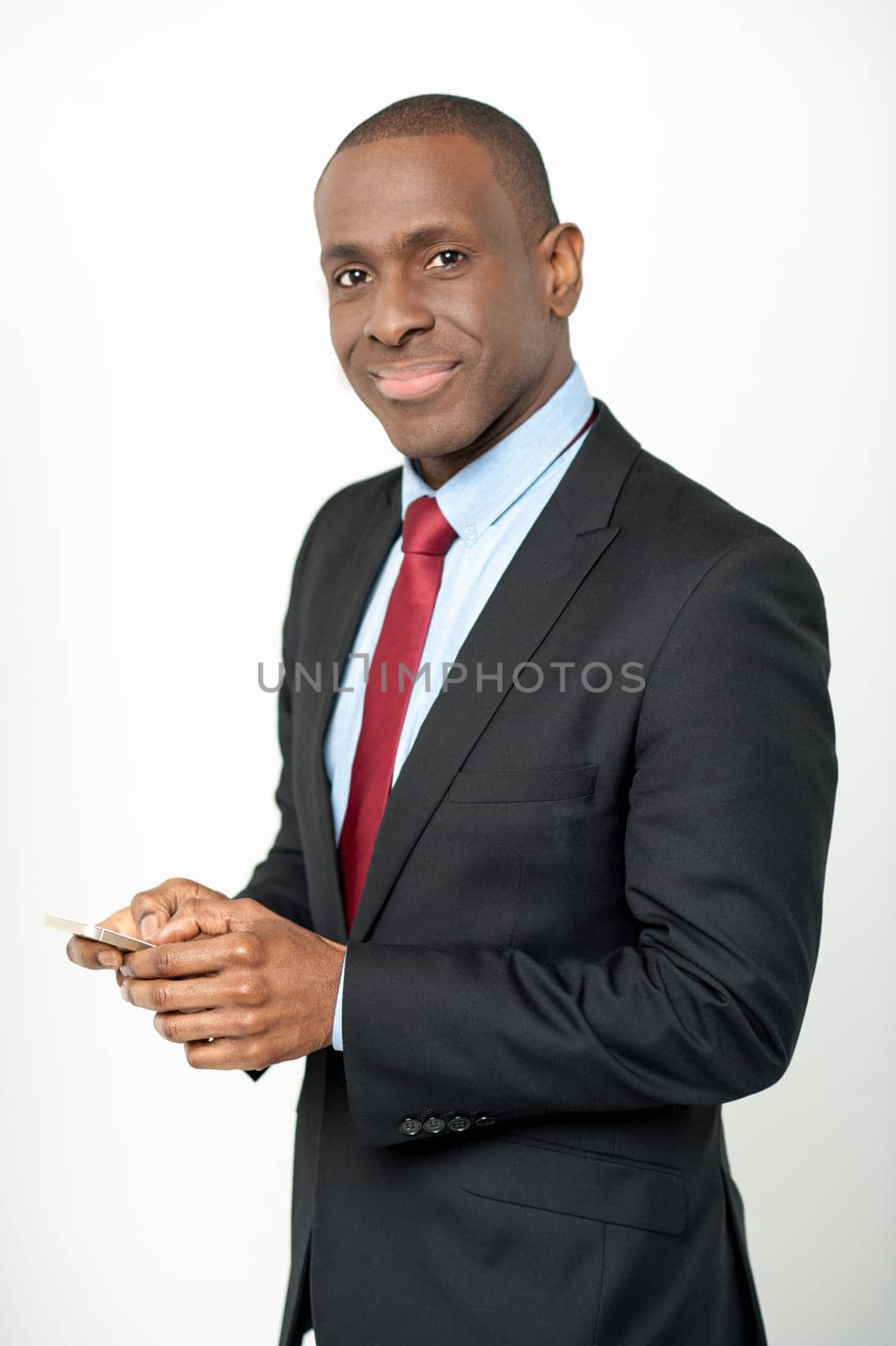 Smiling young businessman holding cellphone over white
