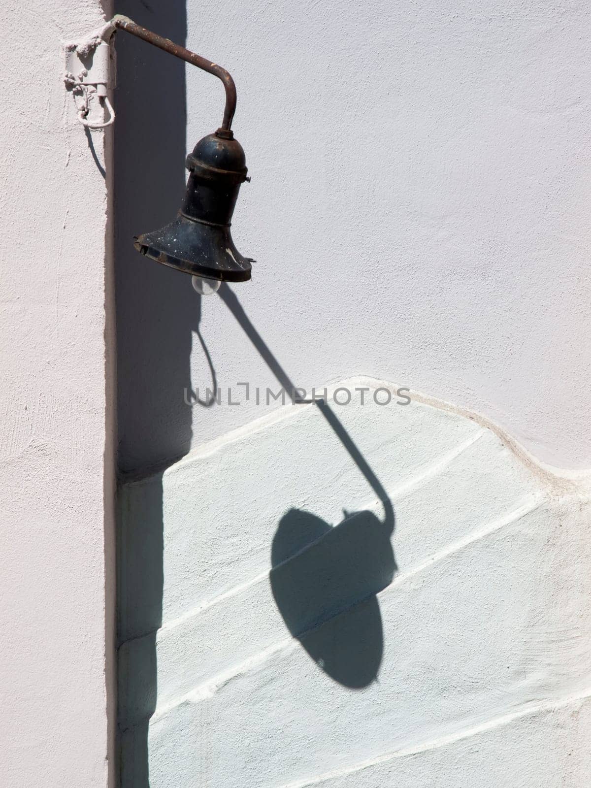 old street lantern throws shtten on a white wall