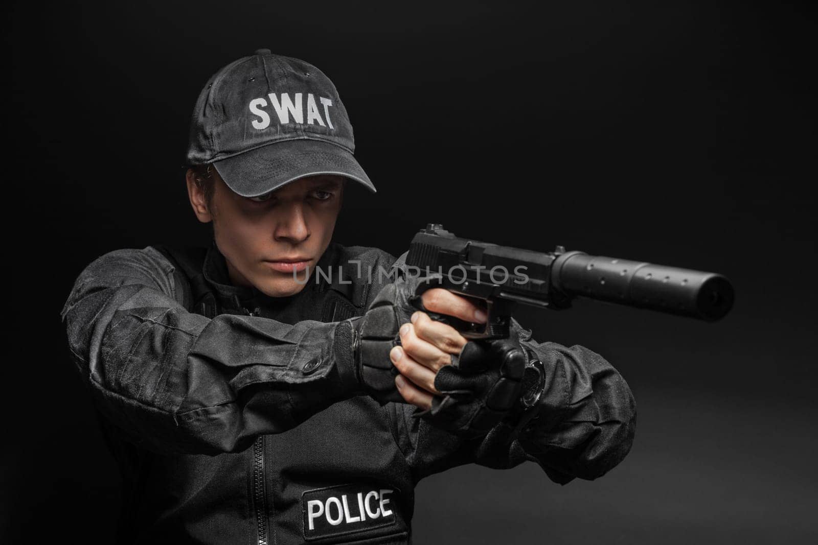 Spec ops police officer SWAT in black uniform with pistol studio