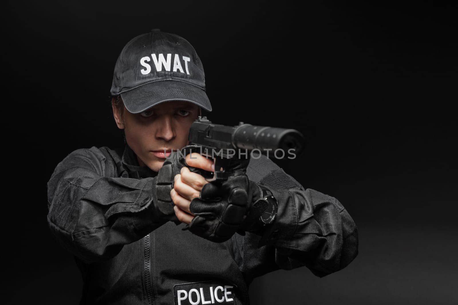 Spec ops police officer SWAT in black uniform with pistol studio