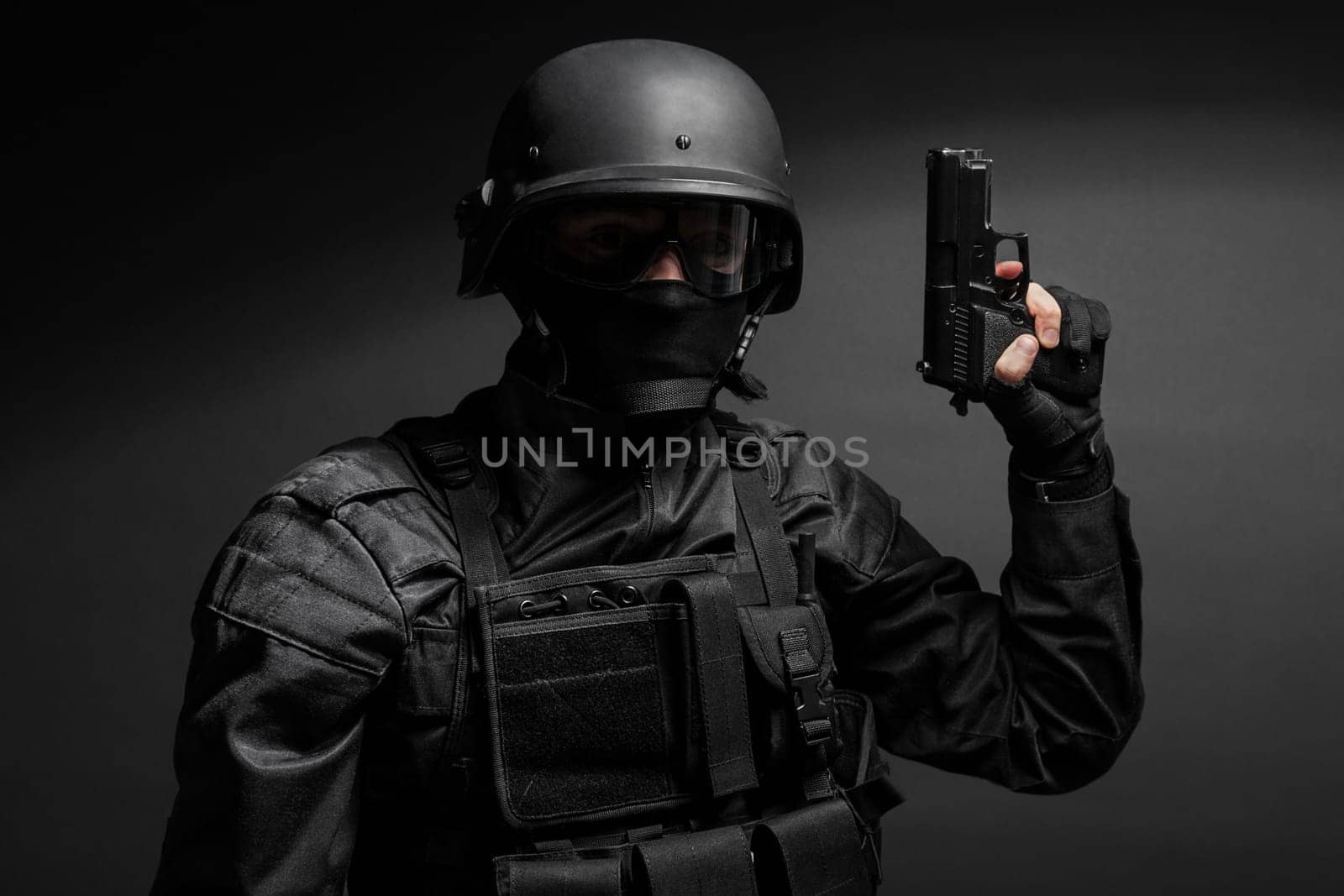 Spec ops police officer SWAT in black uniform with pistol studio
