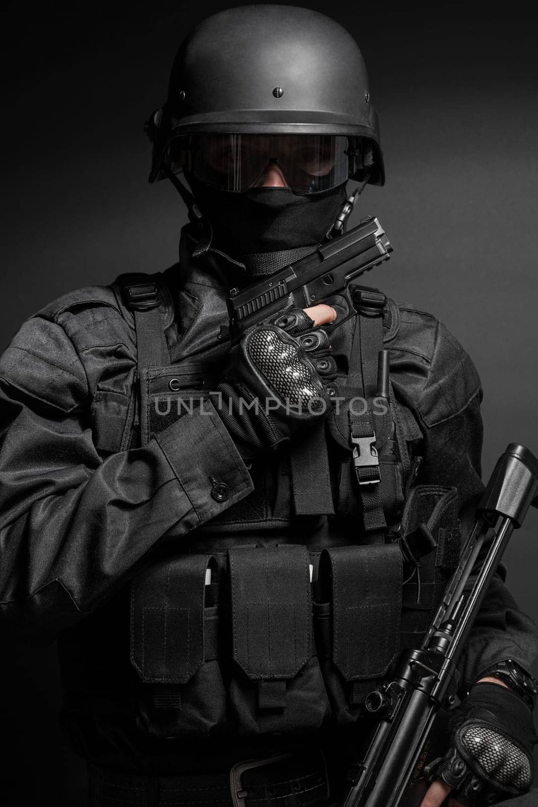 Spec ops police officer SWAT in black uniform with pistol studio
