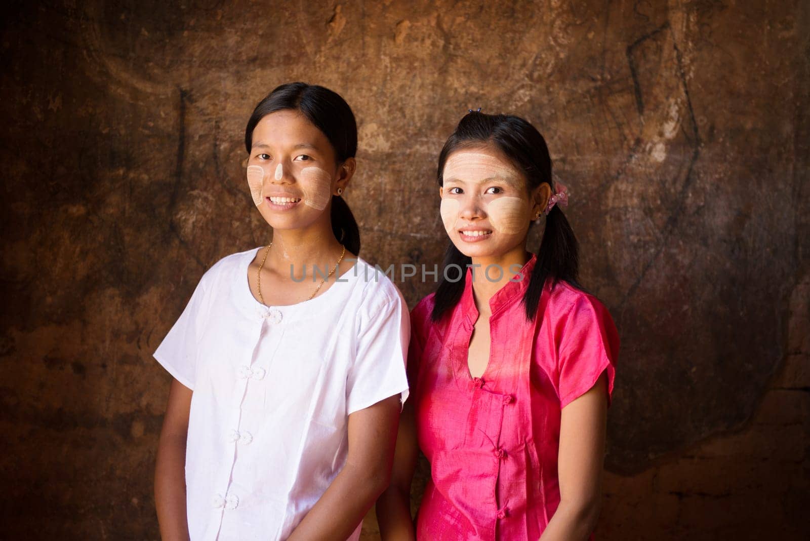 Portrait of two beautiful young traditional Myanmar girls smiling.