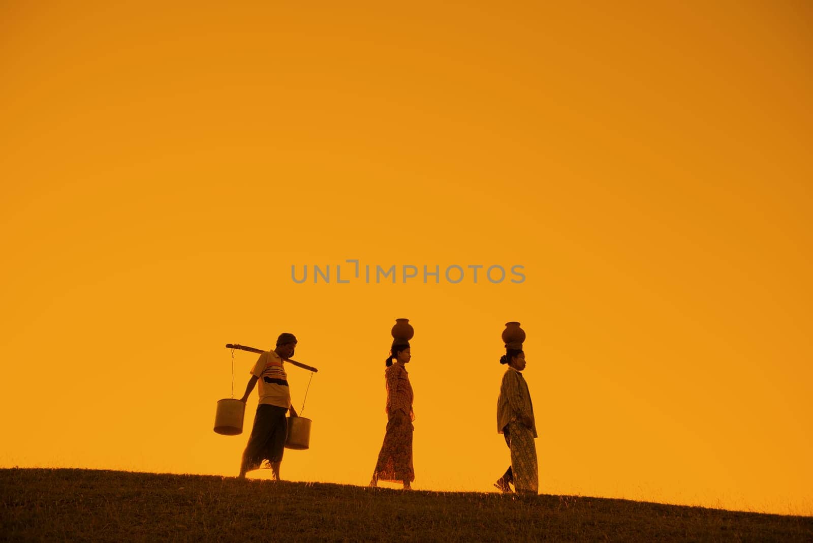 Silhouette of Asian traditional farmers carrying clay pots on head going back home, Bagan, Myanmar