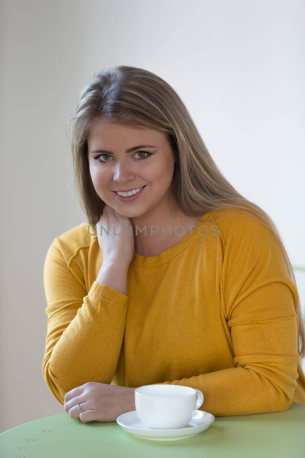 Portrait of a young woman enjoying a cup of tea. She is smiling at the camera.