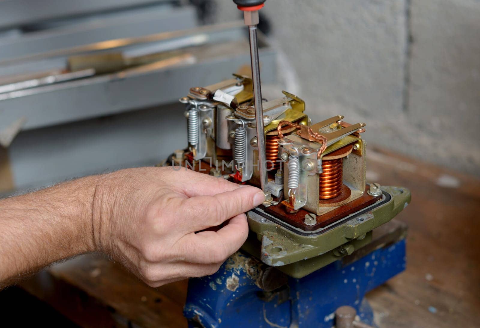 Electrician repairs a regulator of car in his workshop