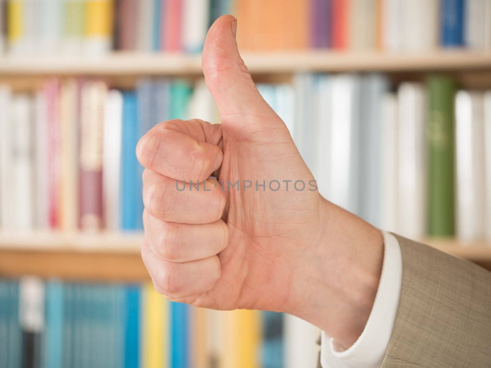 Thumbs up in front of bookshelf