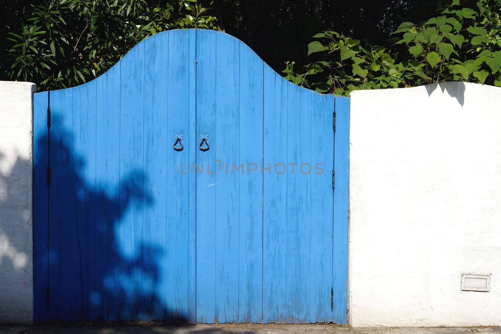 Old wooden blue gateway with white wall