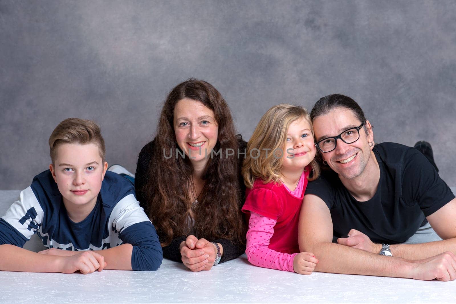 nice family lying on the flor in front of gray background