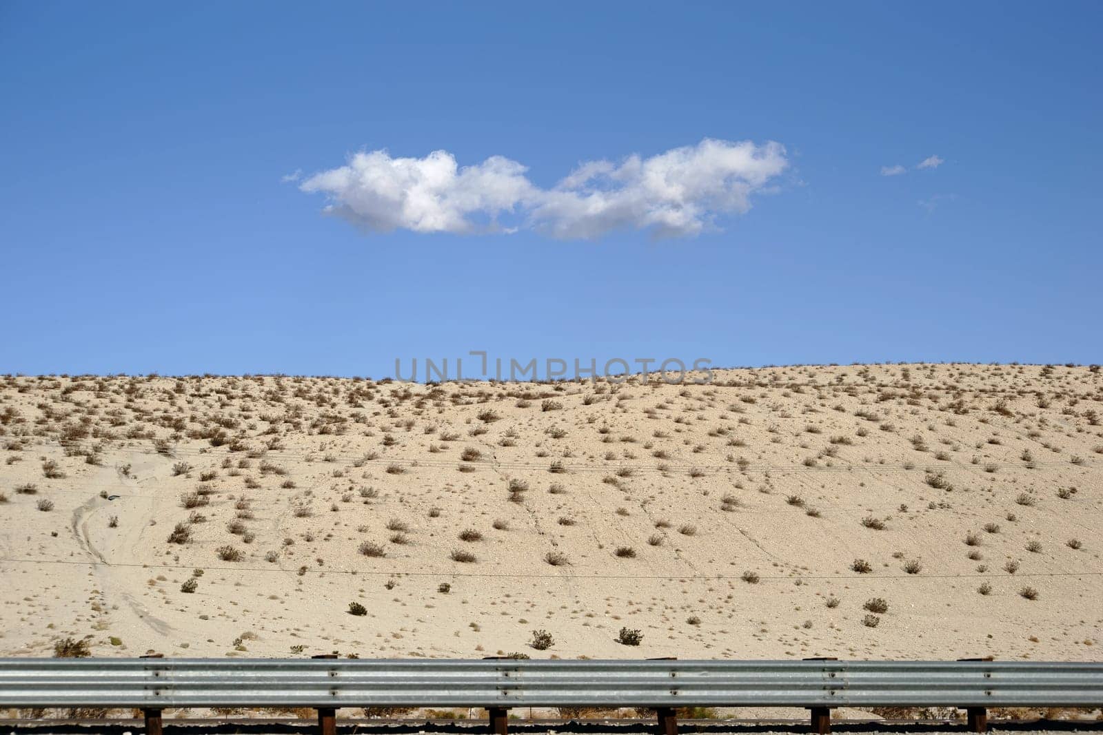 A single cloud over the sand-shaped hills of the desert at Yucca Valley.