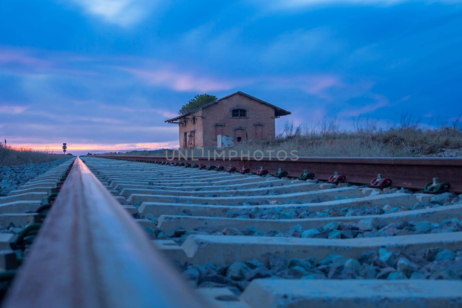 Railway tracks with abandoned rural station at dusk, Badajoz, Spain