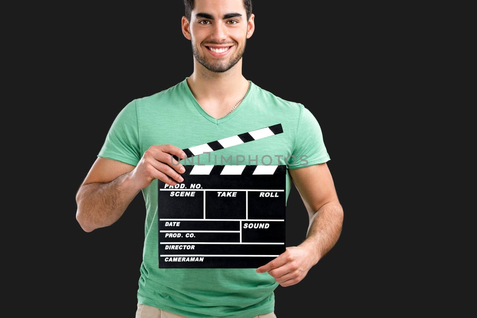 Portrait of handsome young man holding a clapboard, isolated on gray background