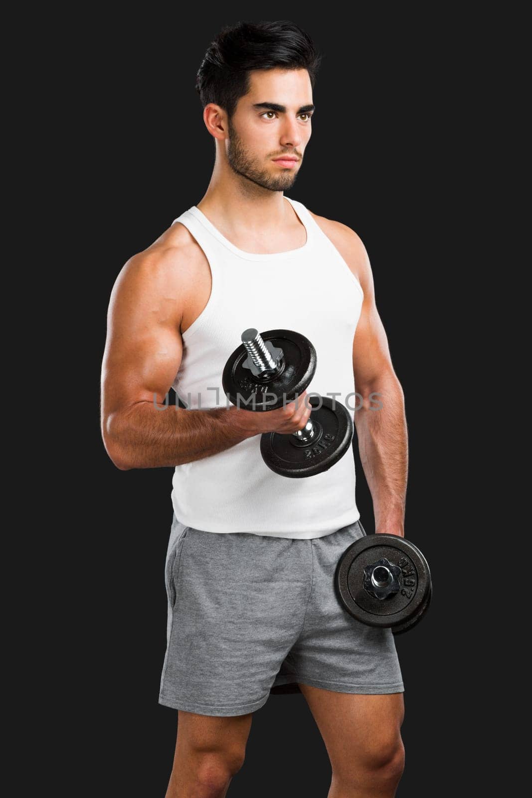 Portrait of handsome young man lifting weights, isolated over a gray background