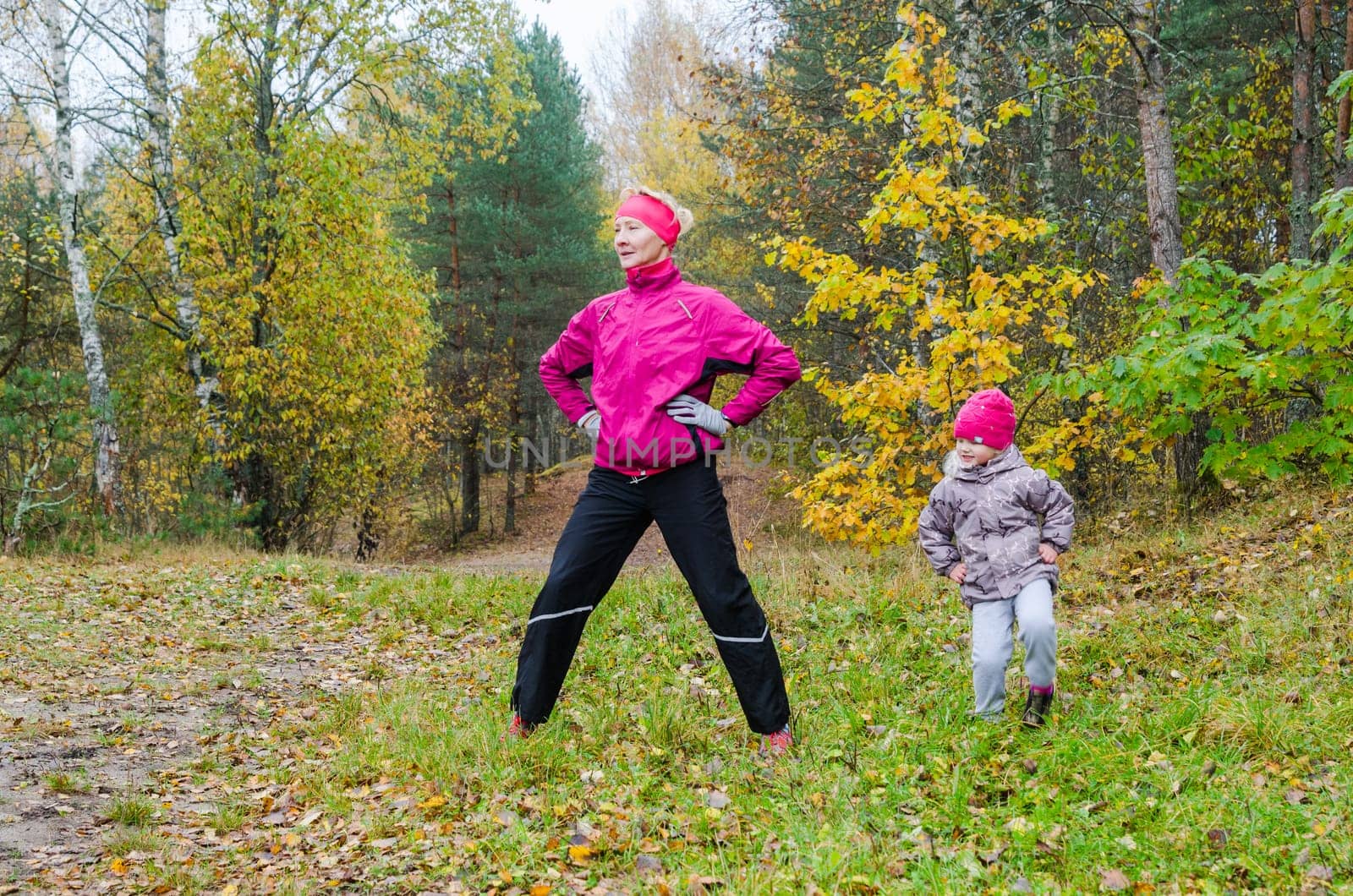 Woman with girl doing aerobics in the autumn park