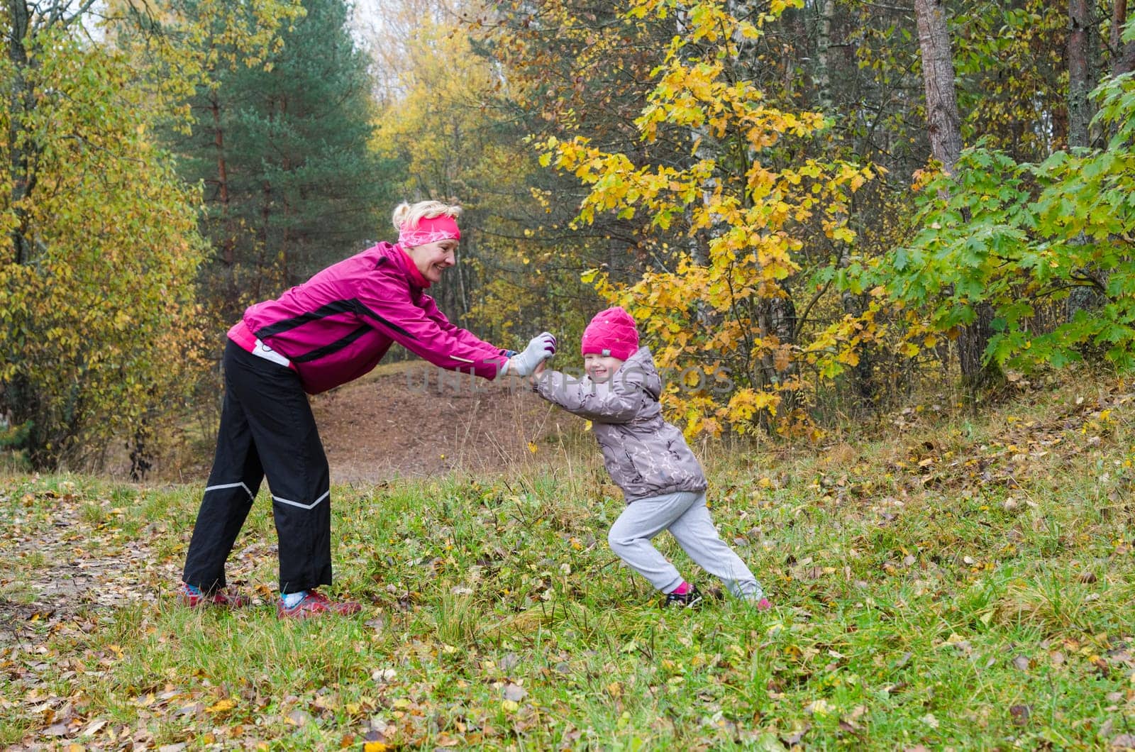 Woman with girl doing aerobics in the autumn park