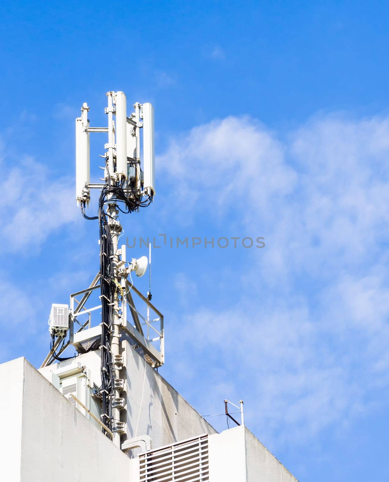 Repeater for mobile phones on top of a building with blue sky and clouds backgrond