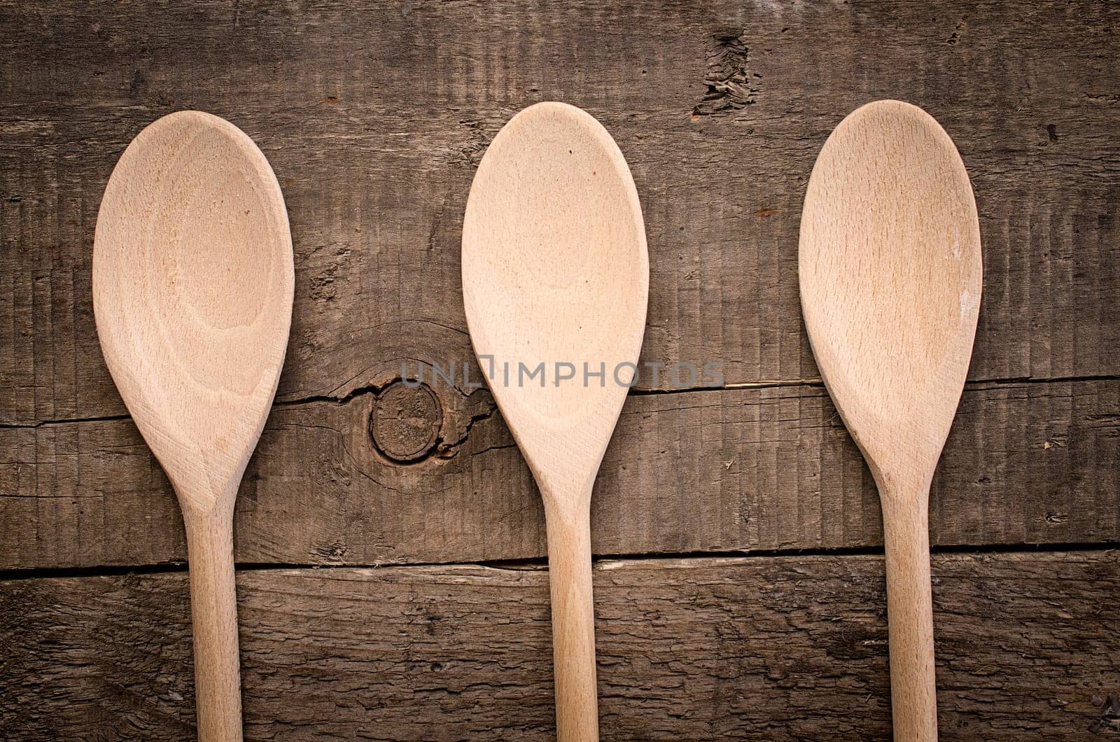 Three empty wooden cooking spoon on a rustic wooden table