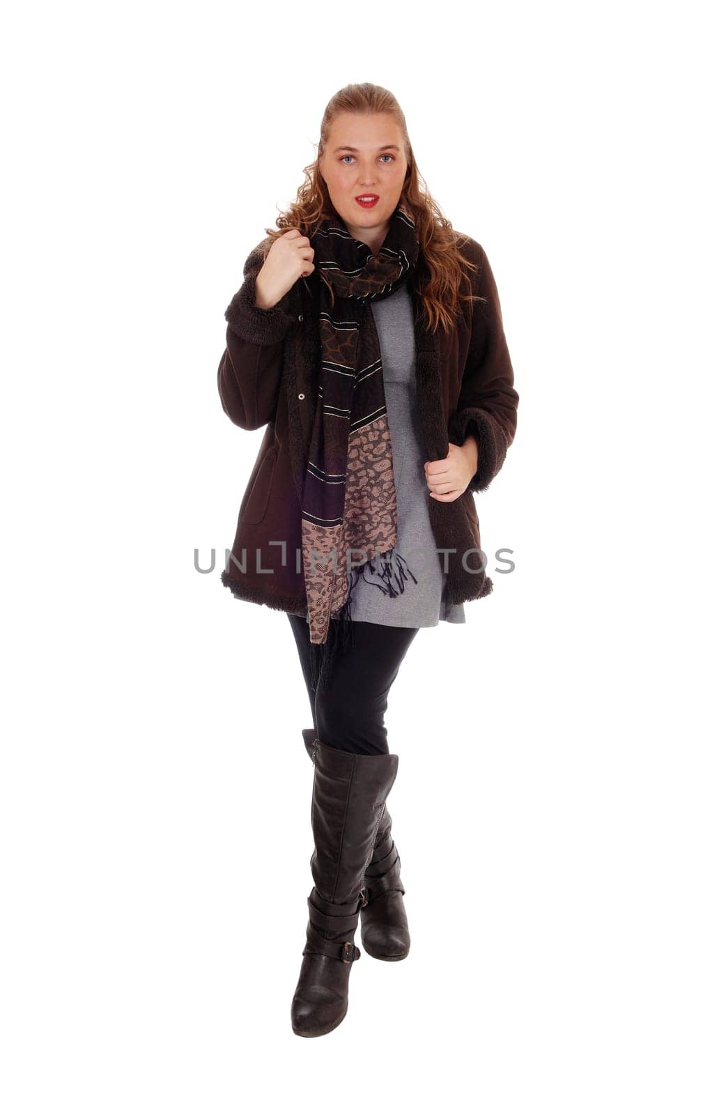 A lovely blond young woman standing in a winter jacket and boots with a.big scarf, isolated for white background..