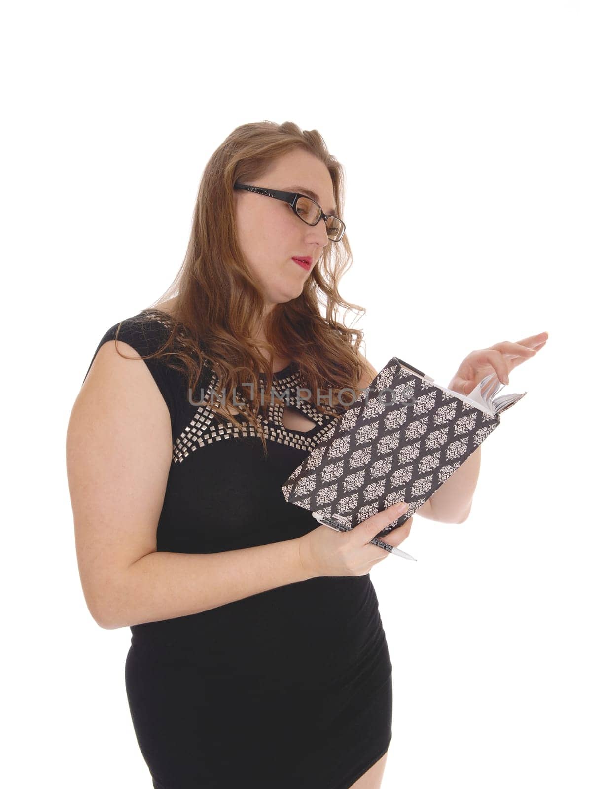 A lovely blond woman standing waist up in a black dress and glasses,.reading in her journal, isolated for white background..