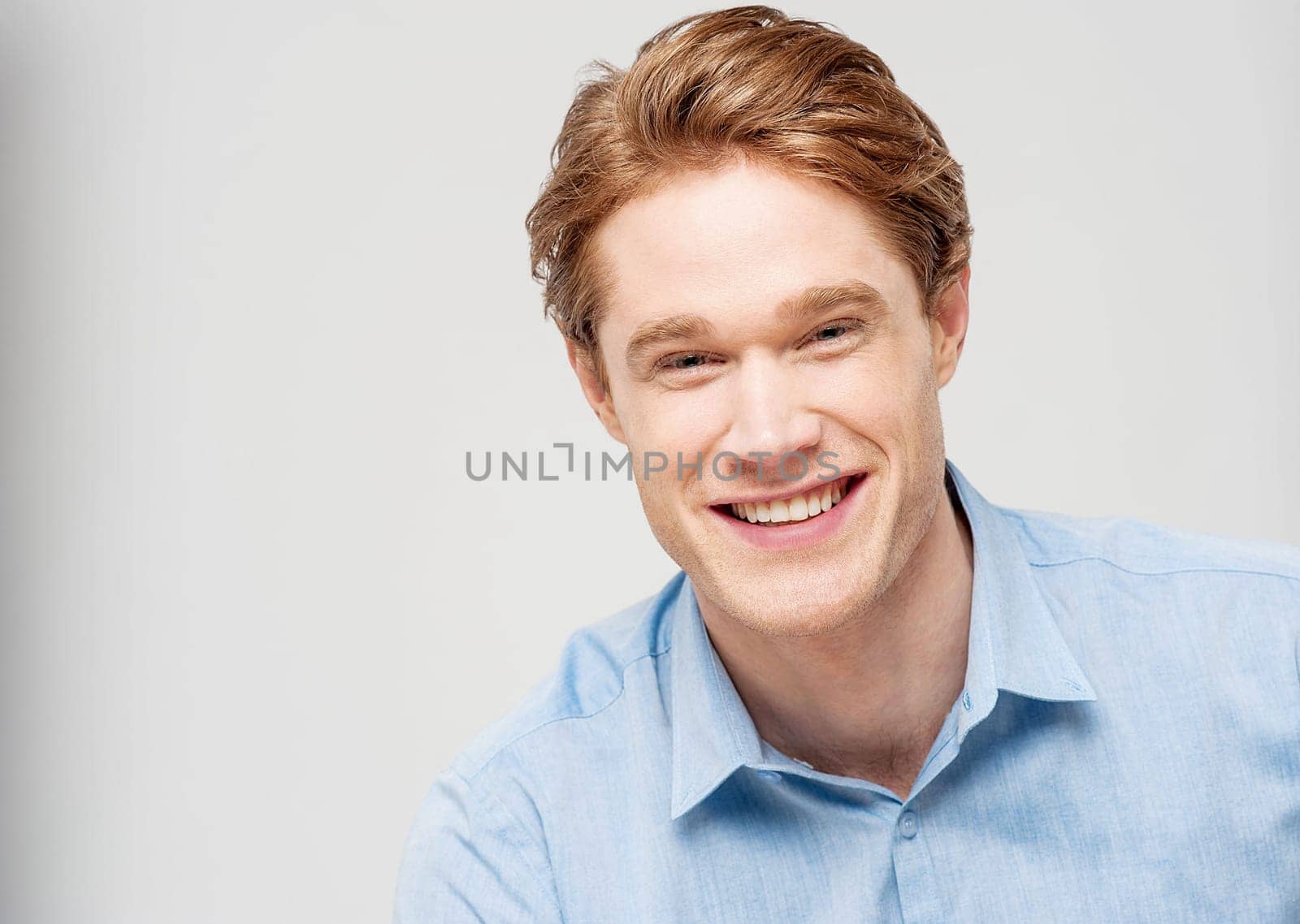 Happy young man smiling at camera over grey
