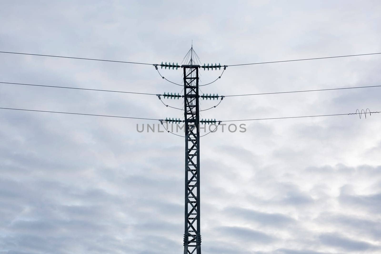 High-voltage steel lattice tower over cloudy blue sky