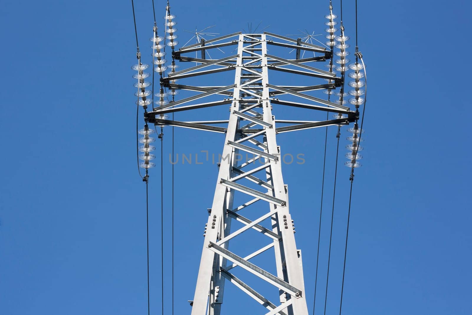 High voltage power pylons against blue sky. Low view