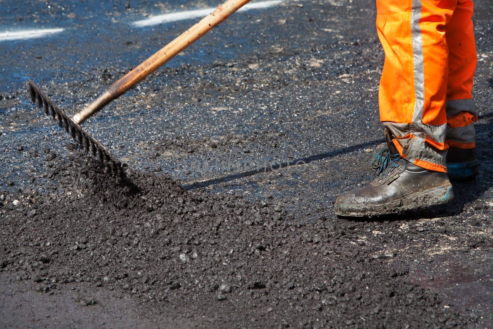 Manual worker leveling asphalt with a rake
